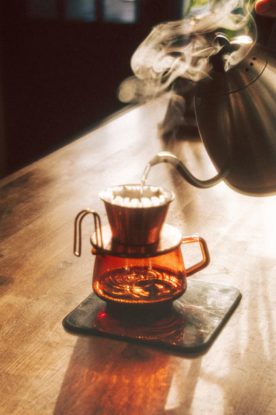 Pour-over coffee in amber glass on a walnut counter